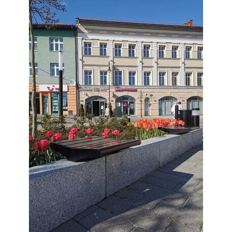 La panchina in metallo con schienale, realizzata in legno di Iroko, è montata su piedistalli o pareti in cemento 'Flow / 001257'